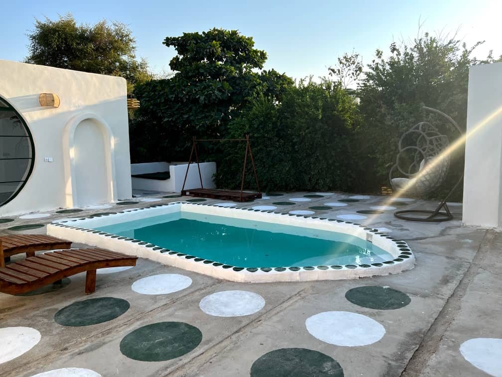 استخر بیضی روباز با کاشی‌کاری سبز در حیاط بوم‌گردی لومبور قشم