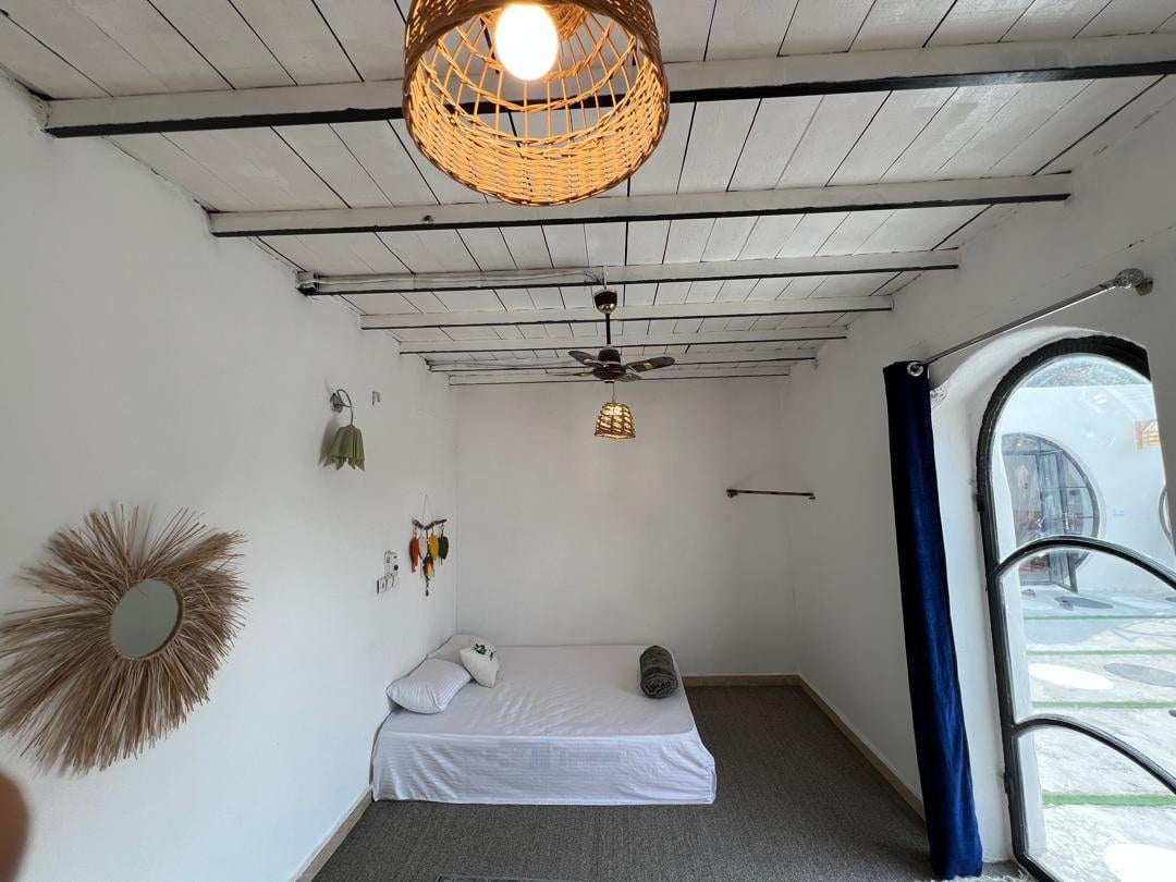 اتاق سفید با چراغ آویز و فرش سنتی در بوم‌گردی لومبور قشم