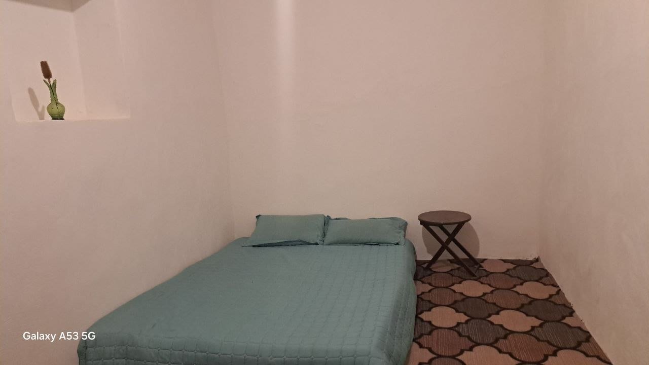 اتاق با تخت سبزآبی و کفپوش سنتی در واحد موچک بوم‌گردی موم گپو قشم