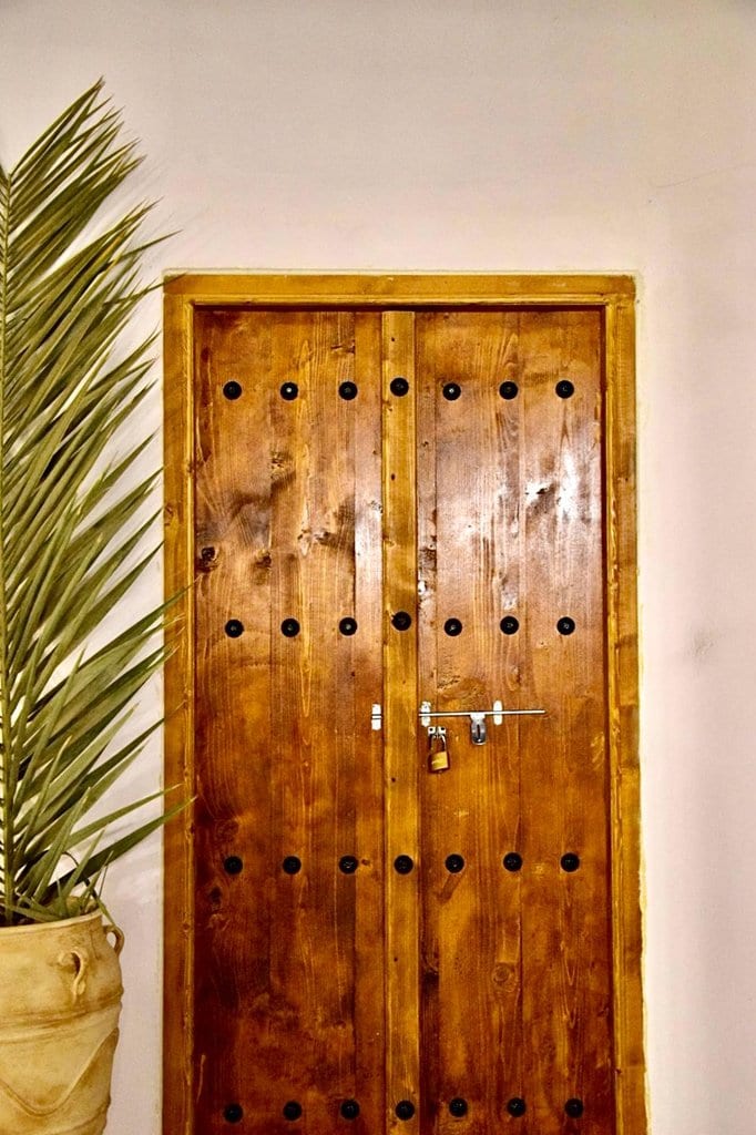 درِ چوبی سنتی دونگله با تزیینات فلزی در بوم‌گردی مغرب قشم