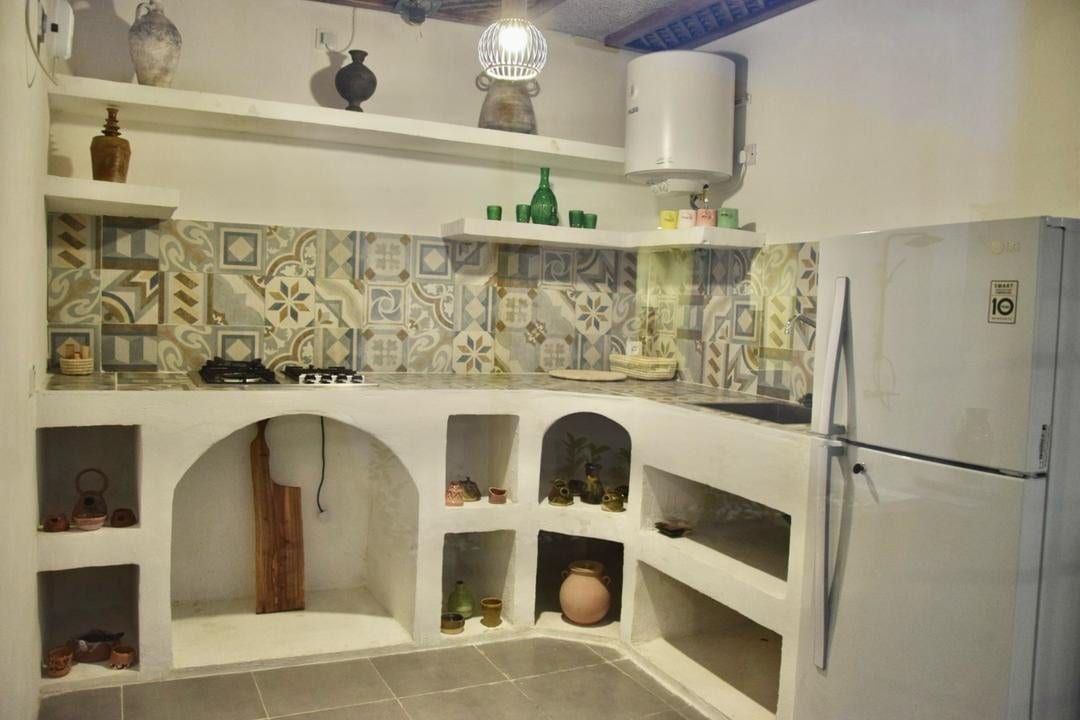 حیاط با آلاچیق و درختان نخل در بوم‌گردی مغرب قشم