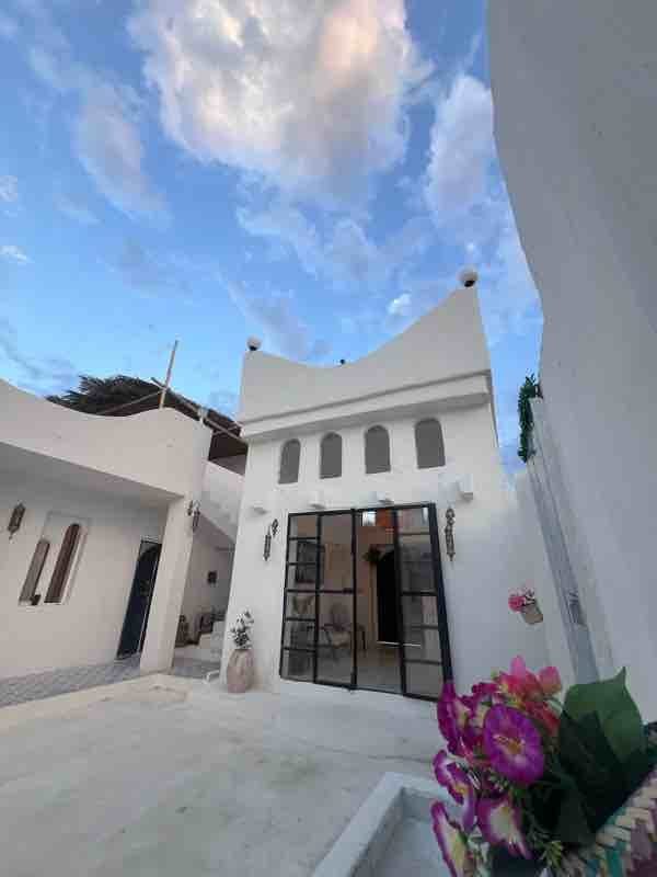 نمای بیرونیِ سفیدِ مدیترانه‌ای ساختمان زیر آسمان آبی در بوم‌گردی مدیترانه سمیره واحد ۴ قشم