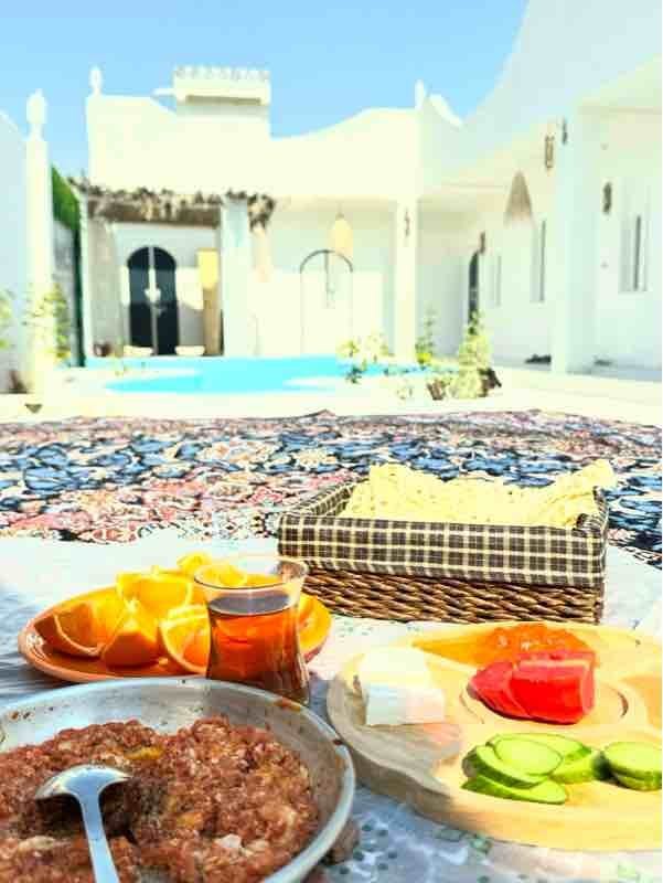 میز صبحانهٔ رنگارنگ کنار استخرِ مجموعهٔ بوم‌گردی مدیترانه سمیره واحد ۶ قشم