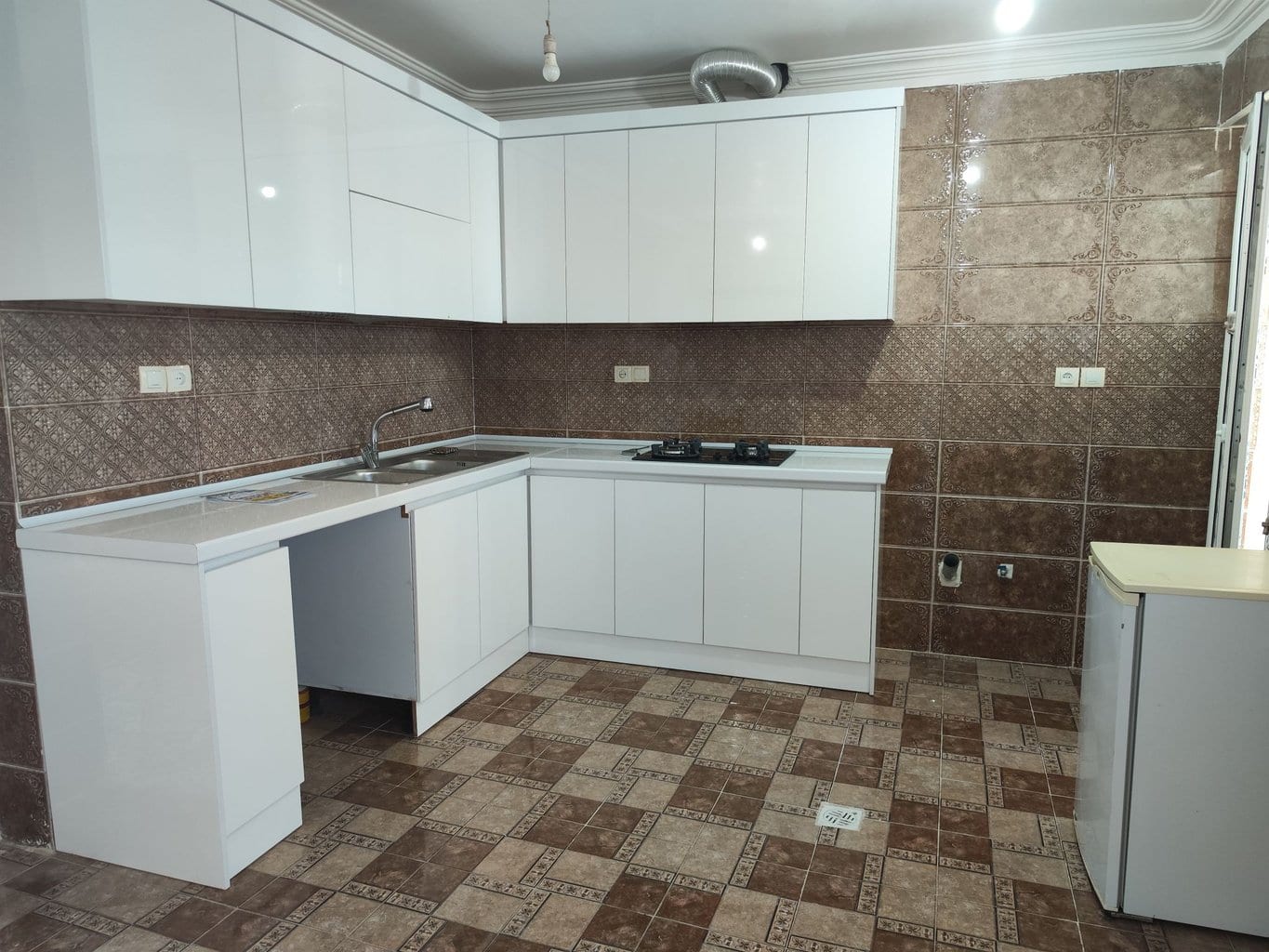 آشپزخانهٔ سفید با کابینت، سینک و گاز رومیزی در سوئیت سنتی سه‌نفره قشم
