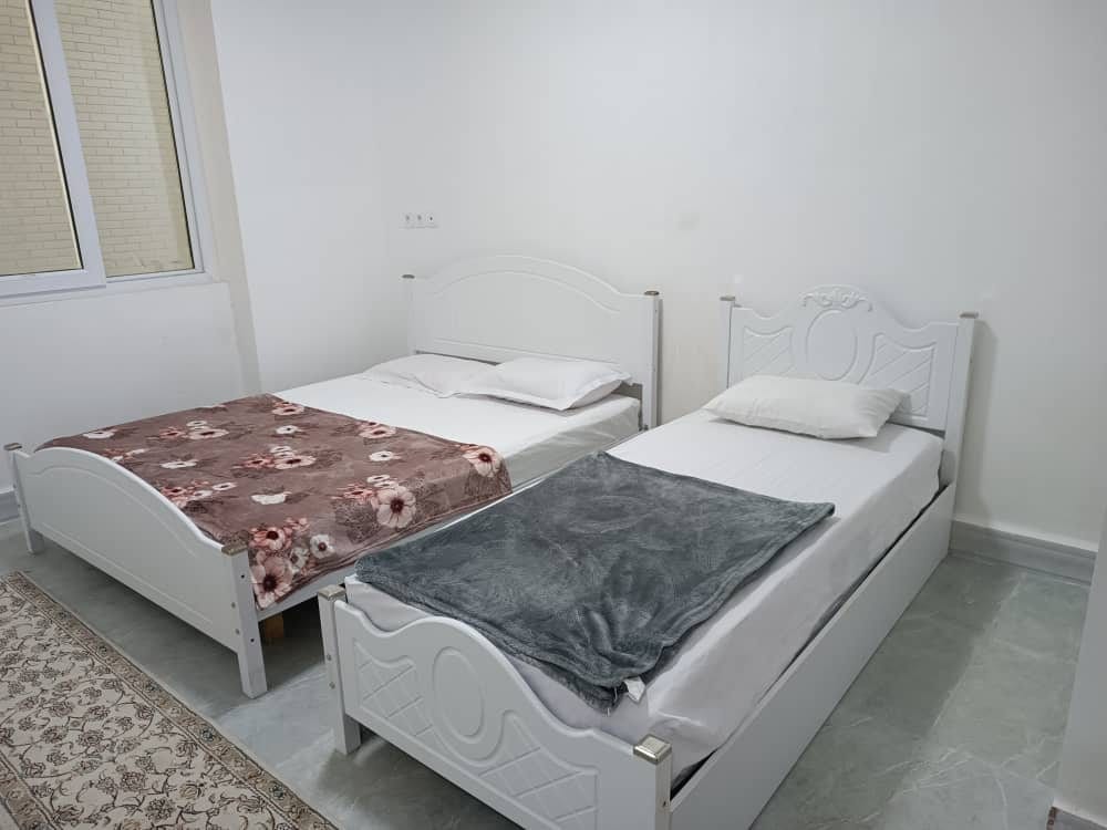 اتاق‌خواب آپارتمان قشم با تخت دونفره و رخت‌خواب سنتی روی فرش