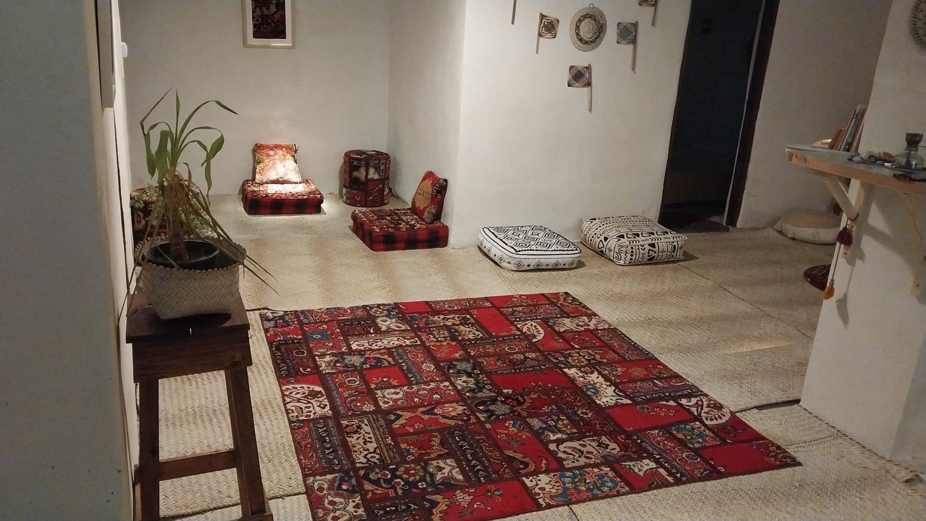اتاقِ پذیرایی با فرش‌های رنگیِ دست‌باف و آباژورِ سنتی در بوم‌گردی کاژه هرمز