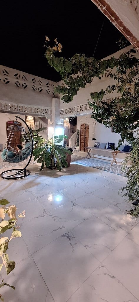 حیاطِ شبانه با طاق‌نماهای نورپردازی‌شده و فضای سبز در سلبار هووس قشم