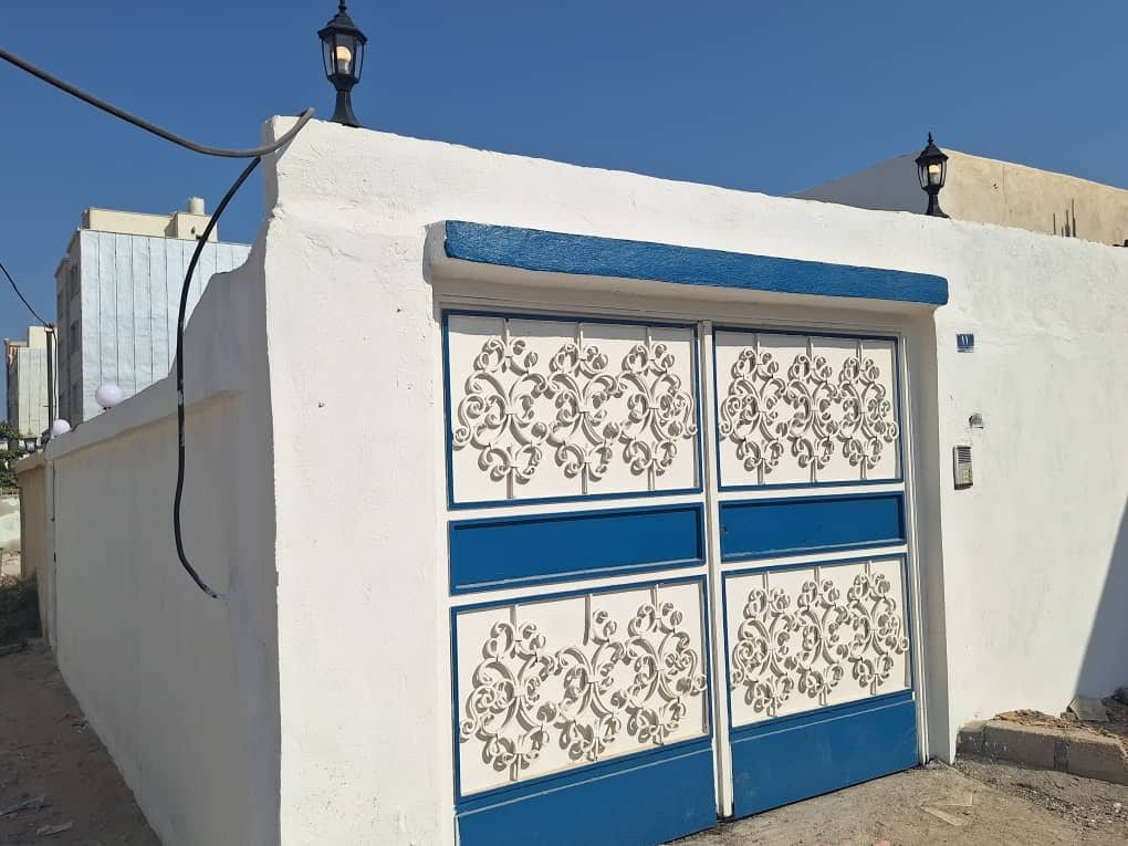 نمای بیرونیِ سفیدِ ویلا عمارت ۶ قشم با درِ آبی