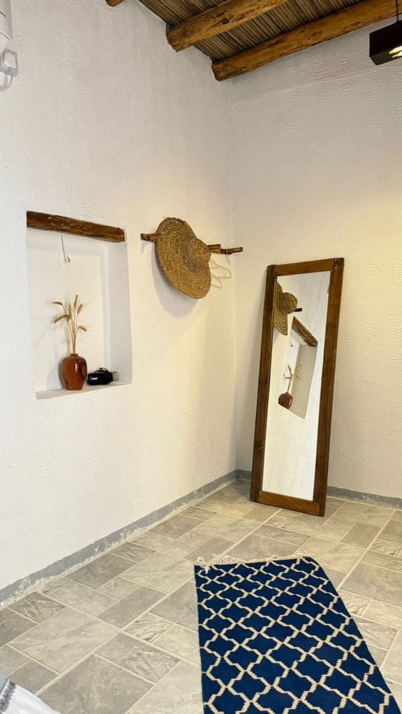 اتاق با درگاهِ قوسی و فرشِ آبی در بوم‌گردی ملو قشم