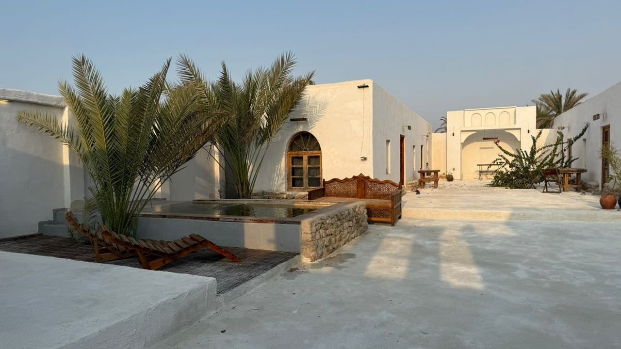 محوطهٔ باز و ساختمانِ سفیدِ سنتی هنگام غروب در بوم‌گردی ملو قشم