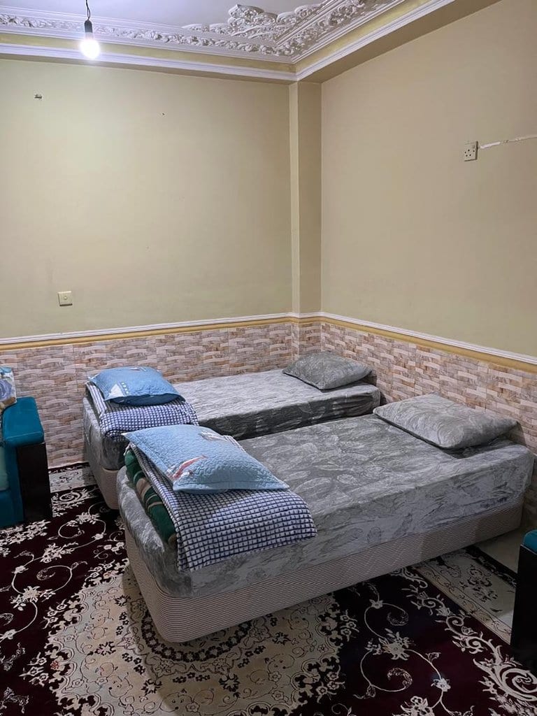 اتاق با تخت‌ها و فرش دستباف در واحد فلت برگ سبز قشم