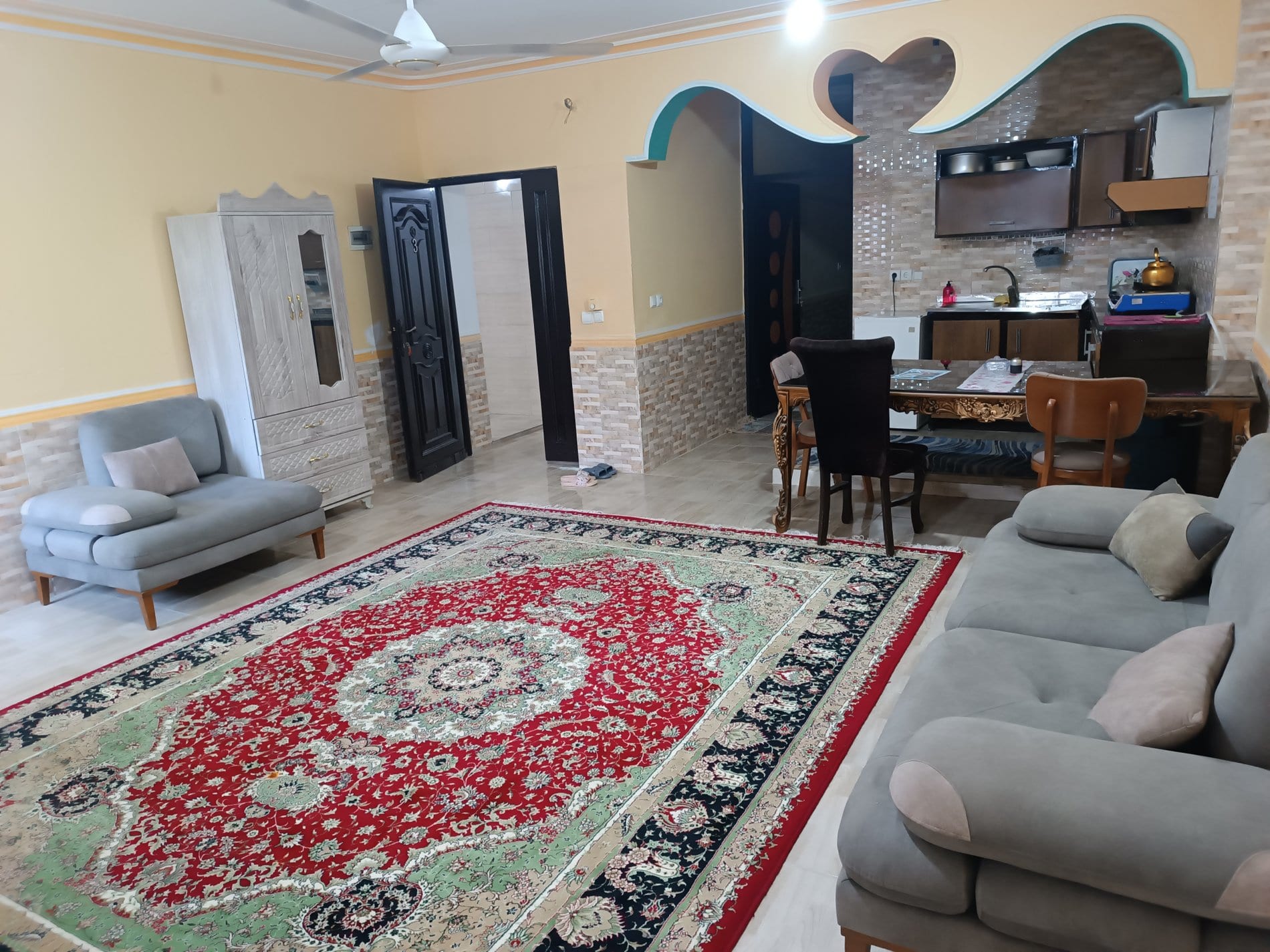 پذیرایی با میز غذاخوری، مبلمان و فرش دستباف در واحد ۳ برگ سبز قشم