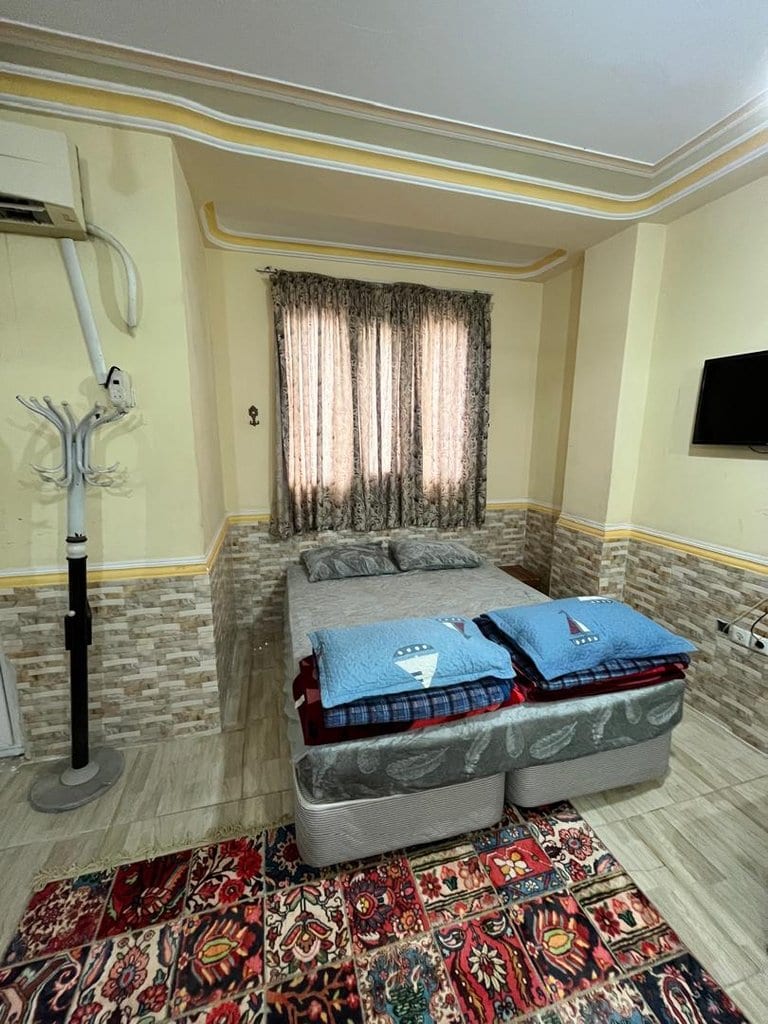 فضای خواب با تخت و فرش دستباف کنار پنجره در واحد ۴ سنتی برگ سبز قشم