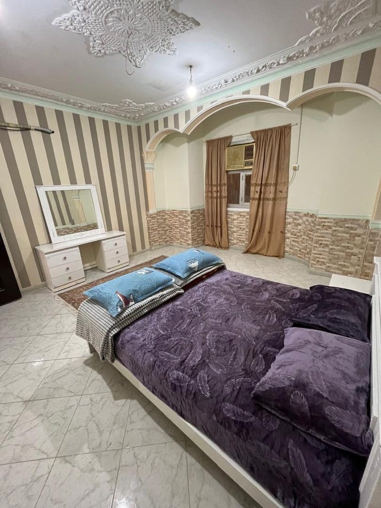 اتاق‌خواب با تخت دونفره میان طاقچه‌های قوسی و میز آرایش در واحد ۶ برگ سبز قشم