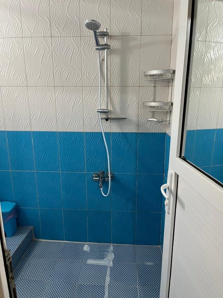 حمام و دوش با کاشی‌کاری آبی در واحد ۸ مجتمع برگ سبز قشم