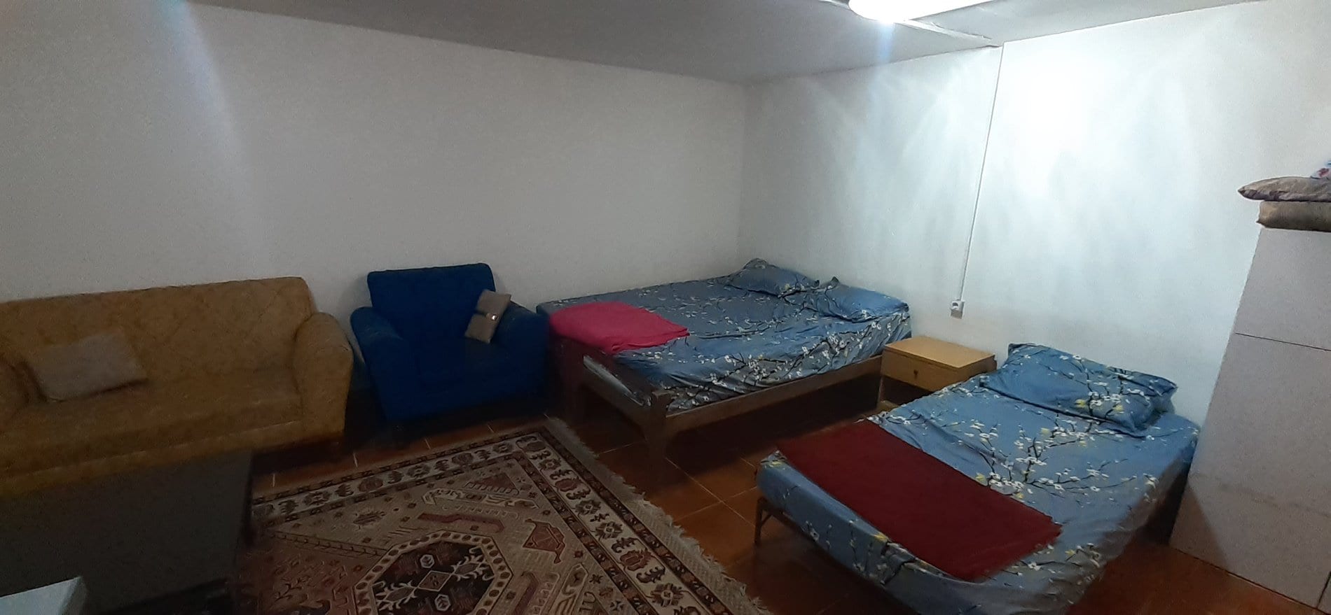 اتاق با رخت‌خواب سنتی پهن‌شده روی فرش در واحد ۳ نخل زرین قشم