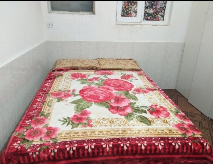اتاق با رخت‌خواب سنتی و روتختیِ گلدار در ویلا سلمان قشم