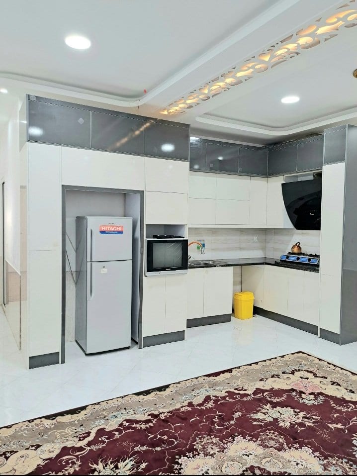 آشپزخانه با کابینت سفید، یخچال و اجاق گاز در ویلا سلمان قشم